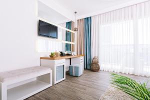 a white living room with a tv and a couch at Ilica Hotel Spa & Wellness Resort in Çeşme