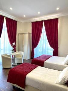 a hotel room with two beds and a desk and curtains at Villa Pallotta Luxury B&B in Cerignola