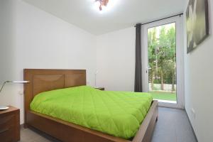 Un dormitorio con una cama verde y una ventana. en Villa Domus, en Son Serra de Marina 16 fotos más