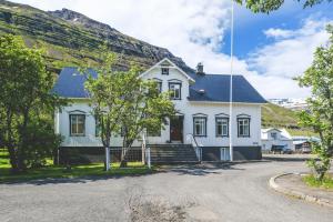 a white house with a mountain in the background at Hotel Aldan - The Bank in Seyðisfjörður