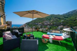 a balcony with a table and an umbrella on the grass at Zaffiro house in Minori