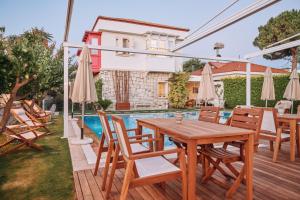 a patio with a wooden table and chairs and a pool at Gobene Alacati in Alaçatı