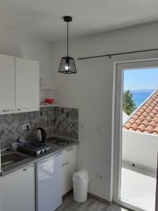 a white kitchen with a sink and a window at Studio Ela in Baška Voda