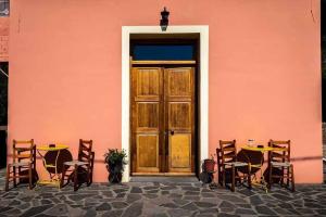 un edificio rosa con una mesa, sillas y una puerta en Arsinoe - Cosy guesthouse- en Methana