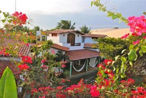 una casa con flores rosas delante de ella en Paracuru Kite Village, en Paracuru