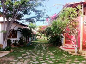 un chemin entre deux maisons plantées d'arbres et de plantes dans l'établissement Paracuru Kite Village, à Paracuru