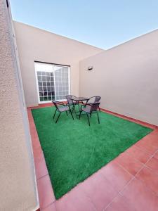 un patio con 2 sillas y una mesa con césped verde en Passion Hotel Villas, en Khamis Mushayt