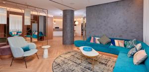 a living room with a blue couch and a chair at Occidental Alicante in Alicante