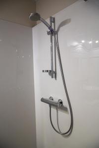 a shower with a shower head on a wall at Bed & Beach Sydney in Middelkerke