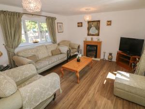 a living room with couches and a table and a tv at Beachway in Holywell