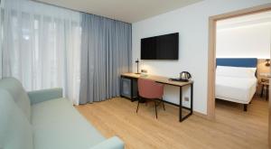 a hotel room with a bed and a desk with a television at Occidental Alicante in Alicante