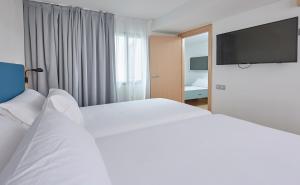 a hotel room with a large bed and a flat screen tv at Occidental Alicante in Alicante