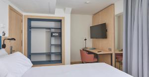 a hotel room with a bed and a desk and a tv at Occidental Alicante in Alicante