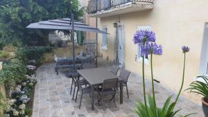 un patio con mesa, sillas y sombrilla en LE CLOS DES COLVERTS, en Campagne-sur-Aude