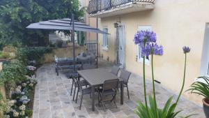 a patio with a table and chairs and an umbrella at LE CLOS DES COLVERTS in Campagne-sur-Aude