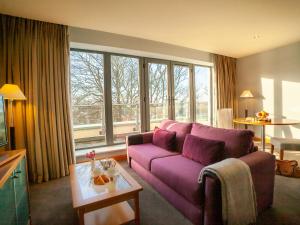 a living room with a purple couch and windows at The Connacht Hotel in Galway