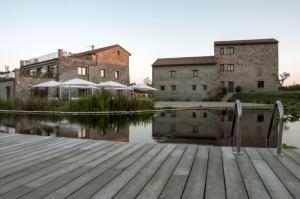 un quai en bois avec une masse d'eau devant les bâtiments dans l'établissement i Cacciagalli Wine Resort, à Teano