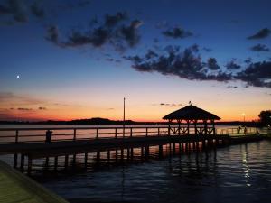 ein Dock mit einem Pavillon auf dem Wasser bei Sonnenuntergang in der Unterkunft Wiking in Kretowiny