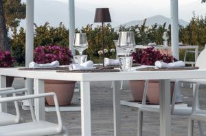 een witte tafel en stoelen met wijnglazen en bloemen bij i Cacciagalli Wine Resort in Teano