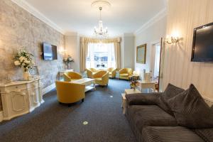 a living room with a couch and yellow chairs at The Carlton in Blackpool