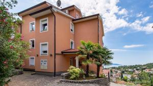 a building with a palm tree in front of it at Rona Spacious apartment with a panoramic view in Ičići