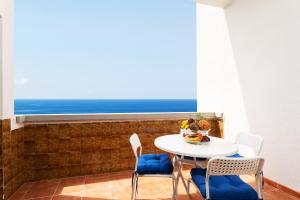 a table and chairs in a room with a view of the ocean at Home2Book Playa Chica Paradise Santa Cruz in Santa Cruz de Tenerife