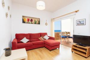 a living room with a red couch and a tv at Home2Book Playa Chica Paradise Santa Cruz in Santa Cruz de Tenerife