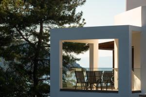 a room with chairs on a balcony with trees at Villa Victoria by La Scala Beach in Limenas