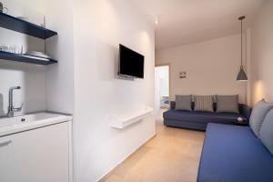 a living room with a blue couch and a tv at Villa Victoria by La Scala Beach in Limenas