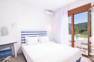 a white bedroom with a bed and a desk and a window at Villa Victoria by La Scala Beach in Limenas +37 photos