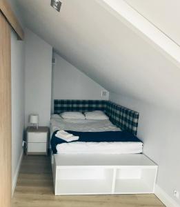 a bedroom with a white bed with a blue headboard at Zastava Apartamenty in Włoszczowa