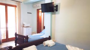 a bedroom with two beds and a tv on the wall at Fistiki Rooms in Agia Marina Aegina