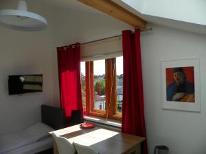 Habitación con mesa y ventana con cortinas rojas. en WILLA HONO LULU en Busko-Zdrój