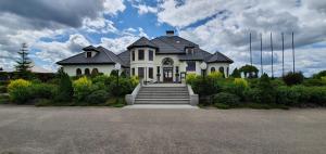 una gran casa blanca con escaleras delante en Bungalows at Sierra Golf Resort, en Wejherowo