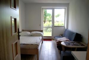 Zimmer mit einem Bett, einem Sofa und einem Fenster in der Unterkunft Rega pokoje in Sarbinowo