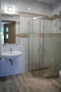 a bathroom with a glass shower and a sink at Rega pokoje in Sarbinowo