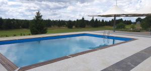 a large swimming pool with an umbrella and anophe at Bungalows at Sierra Golf Resort in Wejherowo