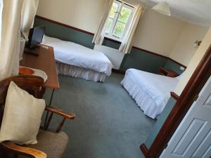ウェイマスにあるThe Lugger Innのベッド2台、デスク、椅子が備わるホテルルームです。