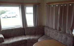a living room with a couch and two windows at Hemsby Long Beach in Great Yarmouth