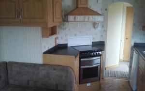 a kitchen with wooden cabinets and a stove top oven at Hemsby Long Beach in Great Yarmouth