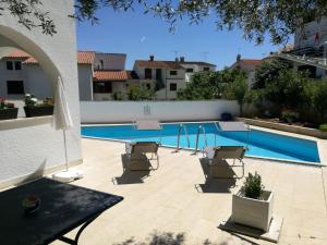 a swimming pool in a backyard with chairs and a table at Ferienhaus Bozena Appartment 1 in Vrsar