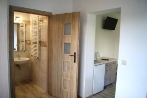 ein Badezimmer mit einer Holztür und einem Waschbecken in der Unterkunft Rega pokoje in Sarbinowo