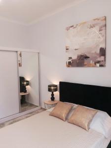 een slaapkamer met een wit bed met een zwart hoofdeinde bij Na Grobli 20 Apartament z ogródkiem in Wrocław