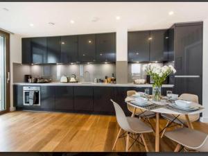 a kitchen with black cabinets and a table and chairs at GRAND SERVICED APARTMENTS***** in Croydon