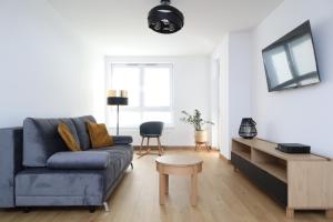 a living room with a blue couch and a tv at Apartament Szmaragdowy Platan in Kołobrzeg