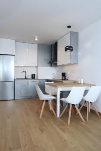 a kitchen with white cabinets and a table and chairs at Apartament Szmaragdowy Platan in Kołobrzeg