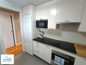 cocina con armarios blancos y encimera negra en Apartamento Izaro, en Mundaka