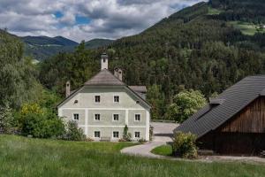 ein großes weißes Haus mit einem Turm auf einem Hügel in der Unterkunft Puenlandhof in Bruneck
