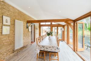 a dining room with a table and a brick wall at Hollyhock House in Stonesfield