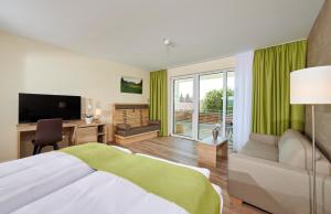 a bedroom with a bed and a desk and a television at Bachhof Resort Hotel in Kirchroth